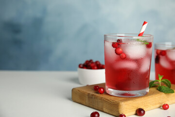 Tasty refreshing cranberry cocktail with mint on white table. Space for text