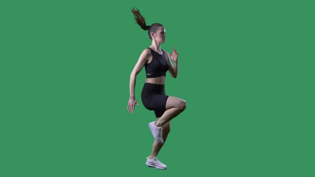 Slow motion side view of athletic woman runner doing high knees exercise. Full body on chroma key green screen. 