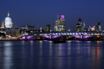 City of London skyline illuminated at night, with the River Thames