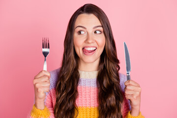 Portrait of attractive cheerful funny brown-haired girl holding fork knife licking lip waiting meal...