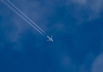Passenger plane in flight, at high altitude, among the clouds. Contrail.