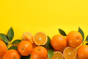 Fresh ripe oranges with green leaves on yellow background, top view. Space for text