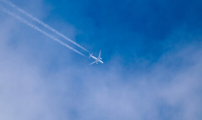 Passenger plane in flight, at high altitude, among the clouds. Contrail.