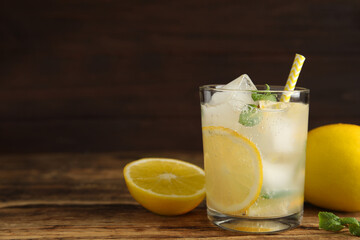 Cool freshly made lemonade in glass on wooden table. Space for text