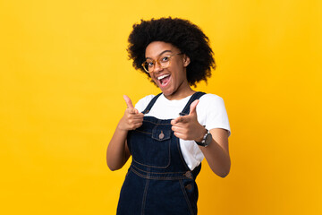 Young African American woman isolated on yellow background pointing to the front and smiling