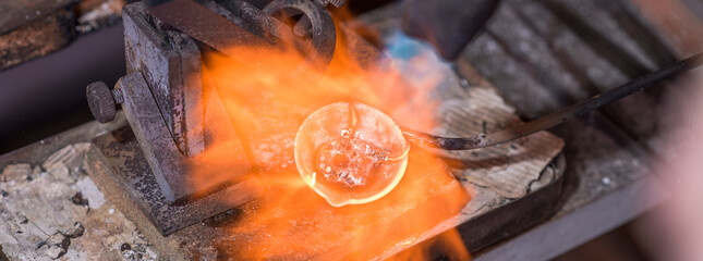 Melting process of precious metal gold behind a jeweler's workbench