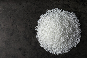 Pellets of ammonium nitrate on grey table, flat lay with space for text. Mineral fertilizer
