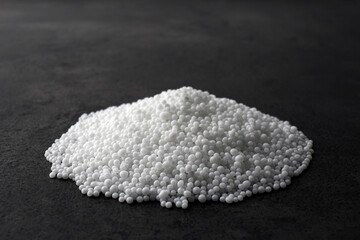 Pellets of ammonium nitrate on grey table. Mineral fertilizer