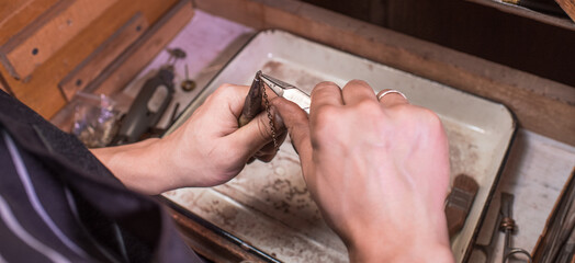 Male hands of a jeweler who weave a gold chain. Chain creation process