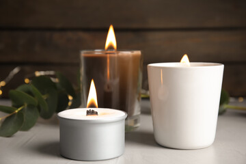 Burning scented candles on light grey table