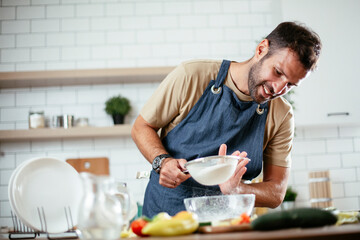 Fototapeta na wymiar Happy man baking in the kitchen. Man making fresh pasta at home