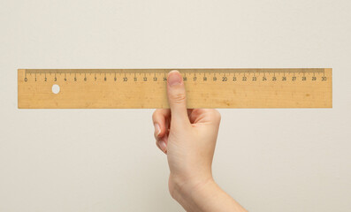 front view, hand holding wooden ruler on isolated background