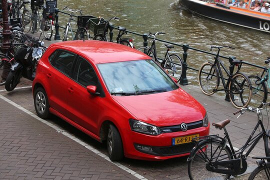 AMSTERDAM, NETHERLANDS - JULY 10, 2017: Red Volkswagen Polo Cross small city car parked by the canal in Amsterdam. Netherlands has 528 registered cars per 1,000 inhabitants.
