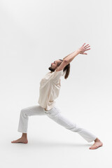 Male yoga teacher practicing in studio. Man isolated on white background doing a stretch exercises