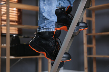 Person climbing ladder indoors, closeup on feet