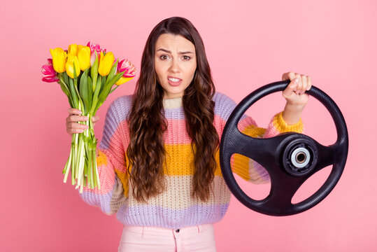 Portrait of pretty worried nervous girl delivering bunch tulips driving invisible car order shop isolated over pink pastel color background