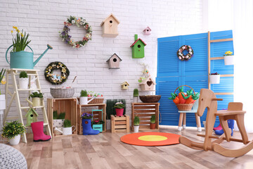 Stylish Easter photo zone with houseplants, rocking horse and blue folding screen