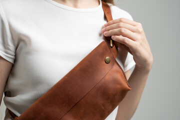 Girl in a white blouse with a leather brown handmade bag over her shoulder. Designer brown banana...
