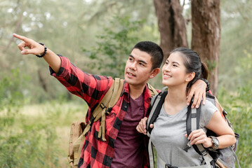 Backpacking and trekking tourism concept, Asian male and female tourists are raising their hands, pointing and gazing into the distance.