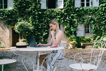 Thoughtful female freelancer working on computer in courtyard