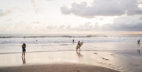 Fototapeta na wymiar Surfers walking on sandy beach