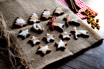 Gingerbread and butter cookies in shape of Christmas tree, stars and reindeer on canvas place mat on wood table background