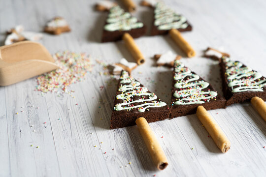 Homemade decorated chocolate brownies in shape of Christmas tree on wood table background