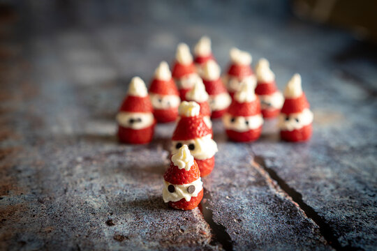 Close-up of cute strawberries shaped as Santa Claus filled with whipped cream and chocolate pieces for Christmas
