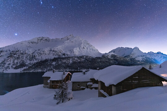 Starry sky over Piz Da La Margna peak and Spluga huts covered with snow, Maloja, Engadine, canton of Graubunden
