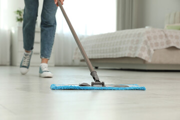 Woman cleaning floor with mop at home, closeup