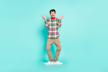 Fototapeta na wymiar Photo of funny clueless guy raise hands look camera wear checkered shirt pants shoes isolated blue color background