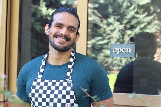 Worker smiling with open signboard in the background