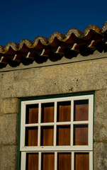 Ventana con carpintería de color blanco sobre fachada de piedra y cielo azul