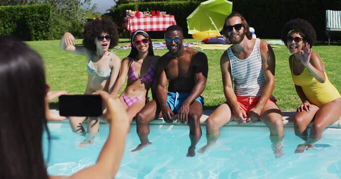 Group of diverse friends posing for a picture while sitting by the pool