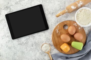 Ingredients and tools for baking and tablet with blank screen and place for text or image on white table. recipe, cookbook, cooking courses online template