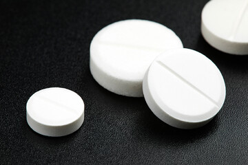 White round pills on black background. Health care concept.