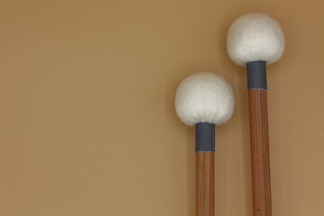 Detail of timpani mallets in the right side on a cream background.