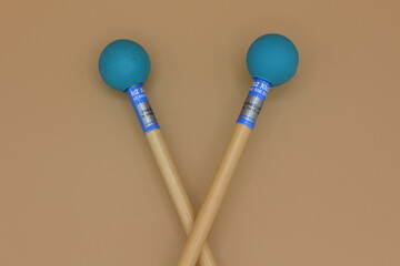 Detail of crossed xylophone
mallets on a cream background.