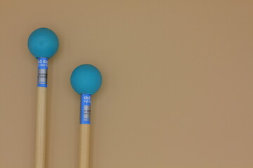 Detail of xylophone mallets in the left side on a cream background.