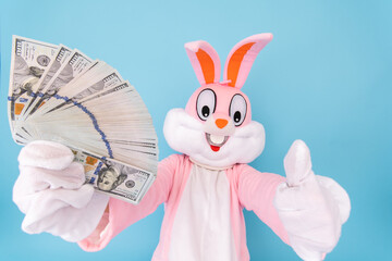 Rich lucky happy man or boy or kid millionaire or billionaire holds fan of dollars, shows thumb finger up, having fun. Easter bunny or rabbit or hare with dollar, celebrate Happy easter