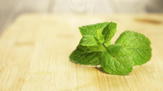 Freshly cut spearmint laid on a small saucer on a wooden surface.