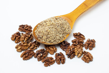 Peeled walnuts and ground walnuts on a white background. A wooden spoon full of ground walnuts. Nutritious food