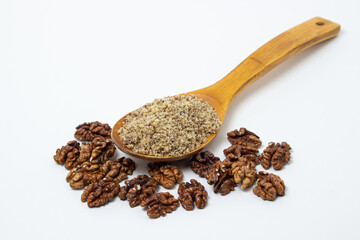 Peeled walnuts and ground walnuts on a white background. A wooden spoon full of ground walnuts. Nutritious food