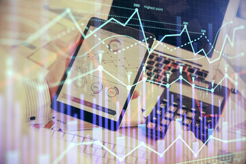 Double exposure of man's hands holding and using a digital device and forex graph drawing. Financial market concept.