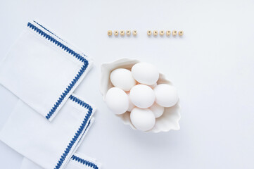 White eggs in a white dish and napkins on the table on a light background. The inscription Happy...