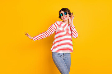 Photo of young beautiful happy smiling excited good mood girl in sunglasses dancing isolated on yellow color background