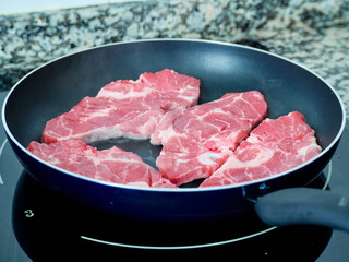 Cooking chops in a frying pan. Grilling raw meat.