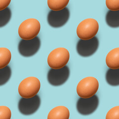 Pattern of brown chicken eggs on a blue background. Minimalism easter, food pattern with hard light and shadows.