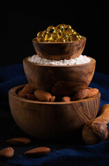 still life, healthy food concept, three bowls with almond nuts, powder and gelatin capsules in the form of a pyramid