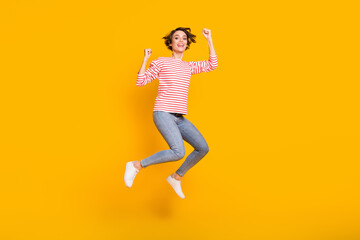 Fototapeta na wymiar Full size photo of young happy positive excited crazy cheerful girl jumping in victory isolated on yellow color background